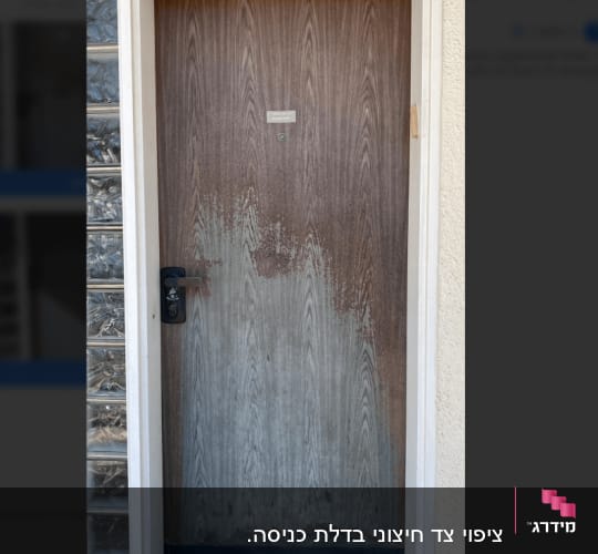 דלת עץ עם קילוף צבע בחלק התחתון